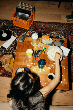 High angle view of woman eating popcorn sitting at messy table