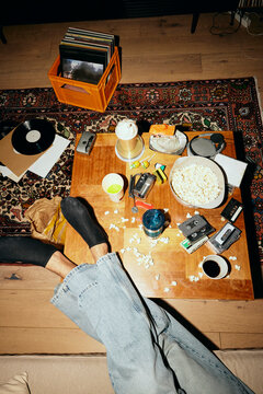 High angle view of young man with feet up on messy table at home