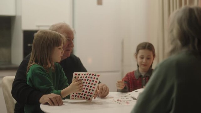 Grandparents and Grandchildren Enjoying a Lively Card Game Together at Home