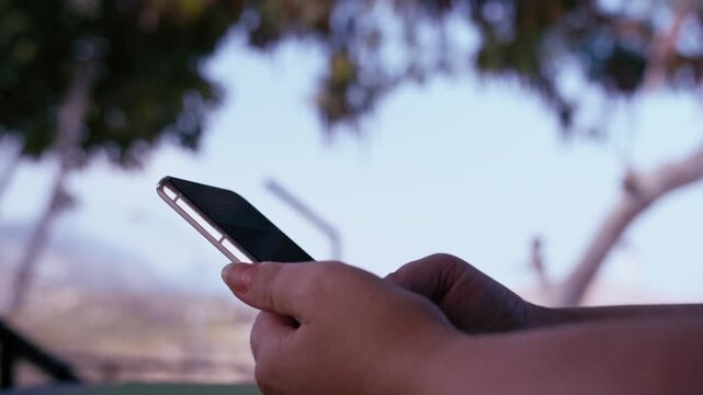 Close-Up of Womans Hands Texting on Smartphone While Relaxing on Veranda with Mountain View