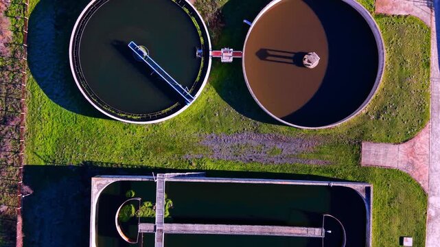 Round concrete clarifier tanks with water during purification process. Top down view of sedimentation tanks at plant.