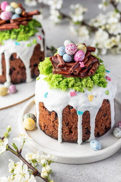 Delicious Easter Kulich cakes with raisins filling with chocolate nest with eggs and edible moss decotation and spring flowers above