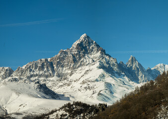 Monviso, or simply Viso, a mountain in the Cottian Alps in Piedmont, Italy, completely covered in snow, stands out above the hills in the foreground on a clear winter's day.
