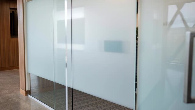Modern glass office door handle opened by hand to reveal conference room business meeting interior inviting collaboration and professional atmosphere