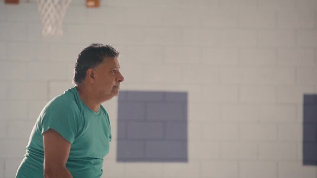 one Indian man playing pickle ball in his middle age. Recreational sports in a high school gym for fun and leisure