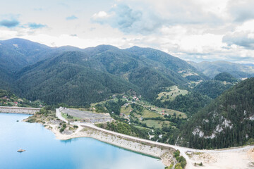 Naklejka premium Mountains and lake with cloudy sky in the background showing a landscape in the daytime with trees and homes nearby