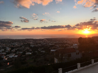 Fototapeta premium Sunset over coastal town with sea horizon in Cyprus. Evening atmosphere, travel inspiration and urban landscape panorama concept
