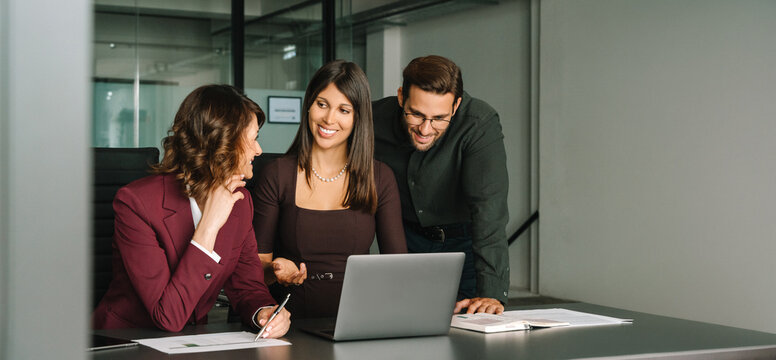 Diverse colleagues coworkers group of professional business people discussing project. Mature Latin business woman and European young team working using laptop computer in office. Banner, copy space