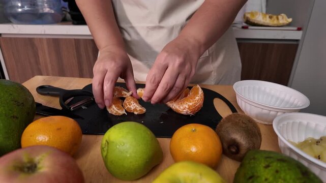 Woman cutting a peeled mandarin into segments