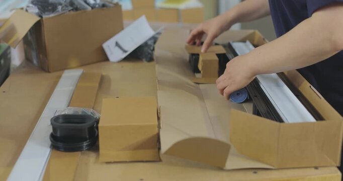 Packing shower drains and sanitary ware into cardboard boxes at a plumbing warehouse. Assembling and packing goods into boxes at a plumbing factory. A packer working at a plumbing factory 