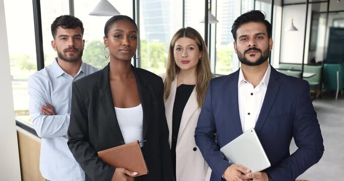 Multinational team staff members, businesspeople posing for camera, standing together in corporate workspace, exuding competence, showing unity. Teamwork, diversity and professionalism in workplace
