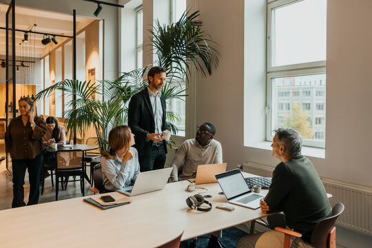 Group of male and female business professionals sharing ideas in team meeting at office