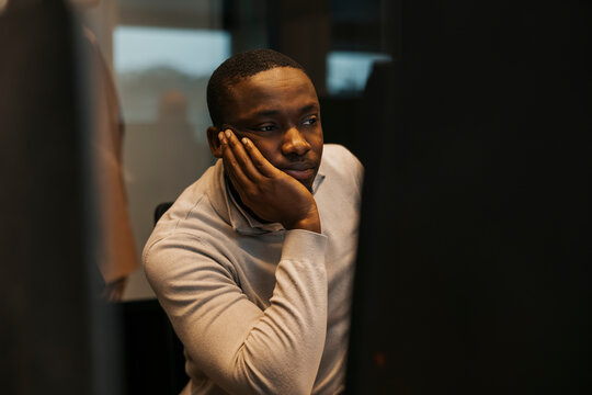 Bored businessman leaning on elbow while working late night at office