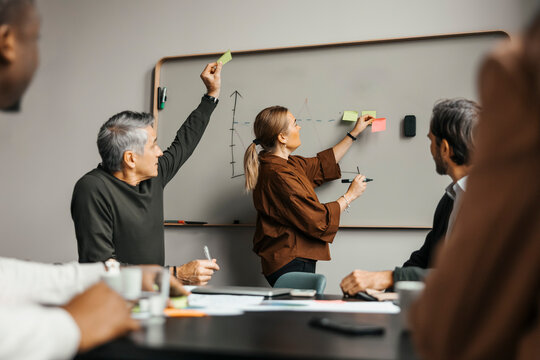 Side view of businesswoman doing brainstorming session with coworkers in meeting