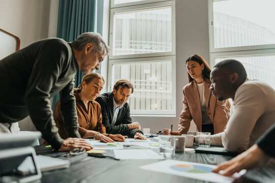 Group of focused business professionals examining reports in meeting at office