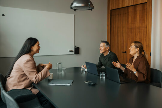 Male and female entrepreneurs communicating with client while sitting at table in office meeting room