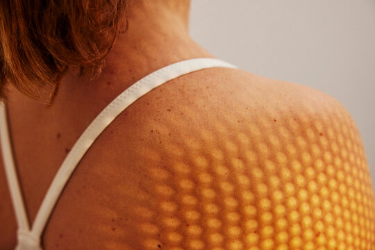 Patterned shadow of sunlight falling on woman's shoulder