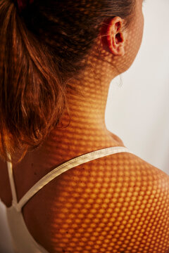 High angle view of patterned sunlight shadow falling on woman's shoulder