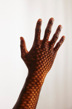 Patterned shadow of sunlight shining on man's hand