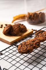 Fototapeta premium Chocolate cookies on wooden cutting board and cooling rack isolated on white background.