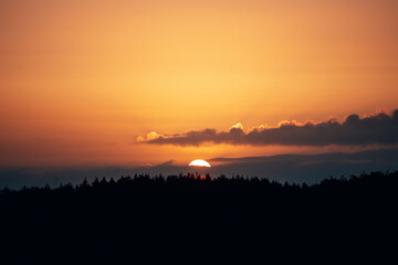 Fototapeta premium Breathtaking Sunrise Over a Dense Forest, Sky Ablaze with Vibrant Red and Orange Hues in Natural Light