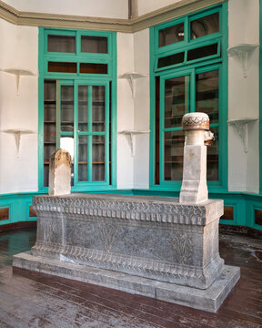 Tomb of Fatima Hatun, Mevlana Complex, Konya, Turkey. Historic stone tomb with intricate carvings, set against vibrant green windows and white walls