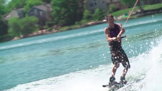 A slow-motion view of a person water skiing with a background of trees growing on a coast
