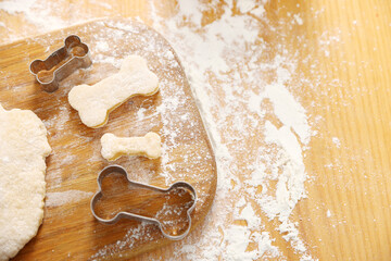 Obraz premium Homemade dog treats. Raw dough and cookie cutters on wooden table, above view. Space for text