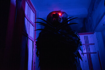 Fototapeta premium Scary Halloween Monster Costume with Glowing Red Eyes in Dark Abandoned Building