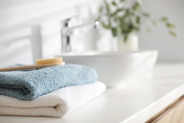 Stack of clean towels and brush on vanity in bathroom, closeup. Space for text
