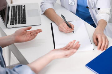 National health service (NHS). Woman having appointment with doctor at white desk indoors, closeup