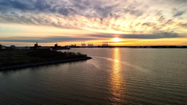 Dramatic sunset over the Elizabeth River industrial harbor and Norfolk Virginia skyline at golden hour
