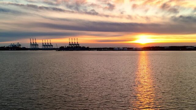 Dramatic sunset over the Elizabeth River industrial harbor and Norfolk Virginia skyline at golden hour