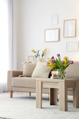 Interior of light living room with sofa, table and spring flowers