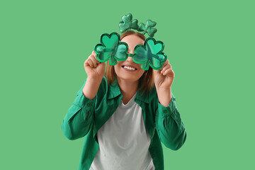 Redhead young woman with clover shaped decor on green background. St. Patrick's Day celebration © Pixel-Shot