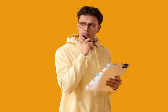 Thoughtful male screenwriter with scenario on yellow background