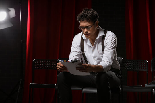 Male screenwriter reading scenario in chair on scene