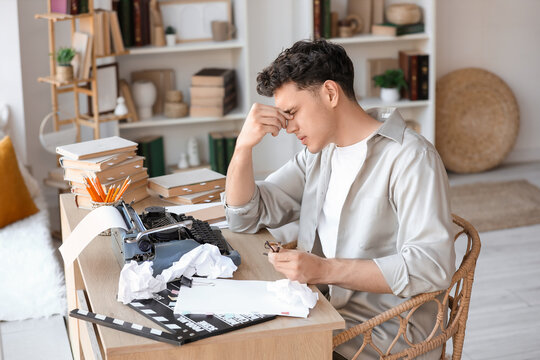 Stressed male screenwriter writing script at table in office