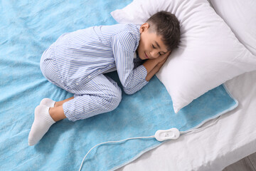 Little boy sleeping on electric heating pad in bedroom, top view © Pixel-Shot