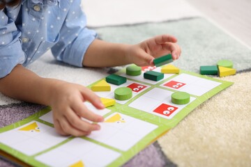 Fototapeta premium Little girl playing with educational toy on colorful carpet, closeup