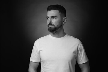 Obraz premium Serious man on dark background with spotlight. Black and white effect