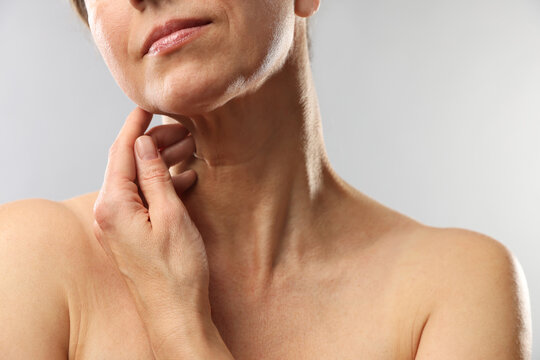 Woman touching her neck on light grey background, closeup