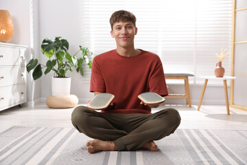 Fototapeta premium Young man with sadhu boards sitting on floor at home