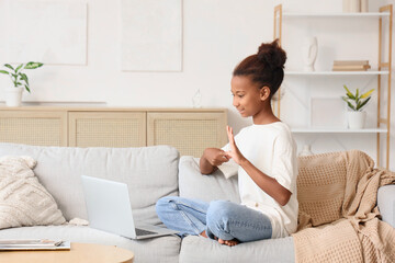 Teenage African-American girl using sign language while video chatting at home