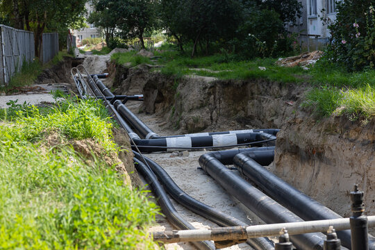 Repair of underground water supply pipelines for apartment buildings in urban residential area with open trench and new plastic pipes. Utility service upgrade and city renovation