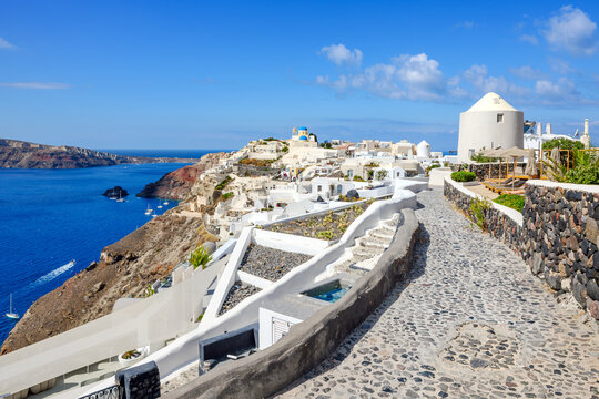 The blue dome churches rise above the whitewashed buildings and terraces overlooking the sea and volcanic caldera in Oia, Greece, on the island of Santorini.