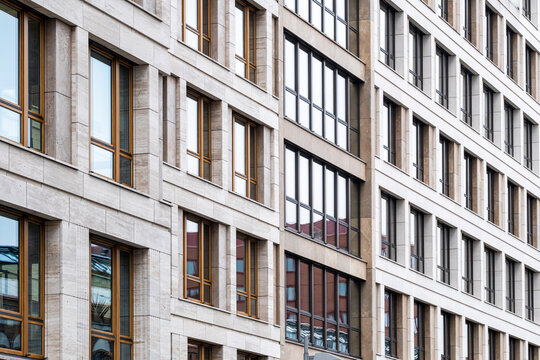 Abstract architecture detail of urban building facade where windows create grid pattern over stone texture forming vertical structured rhythm
