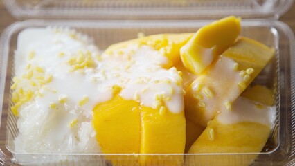 mango sticky rice with coconut milk in plastic box on wooden table - Thailand food