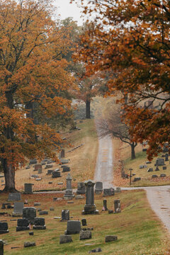 A cemetery surrounded by fall leaves and colorful trees in October.