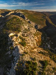 Obraz premium Vertical aerial view of the ancient medieval fortress on a mountain ridge. Epic historic ruins overlooking a deep canyon at sunset. Stjepan-grad, Blagaj, Bosnia.